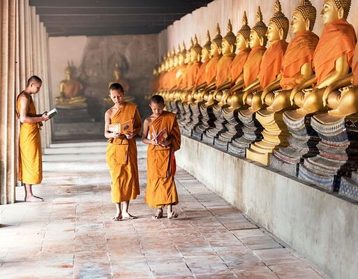 Bildmittelpunkt: Drei junge buddhistische Mönche in einem Kloster in Kambodscha | rechts: lange Reihe mit Budda-Statuen
