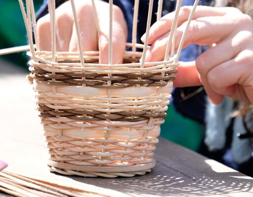 Zwei Hände beim Korbflechten | Korb in natur mit dunkelbraunen Streifen
