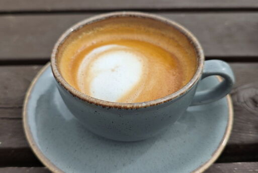 Kaffeetasse aus Keramik mit taubenblauer Glasur, gefüllt mit einem Cappuccino