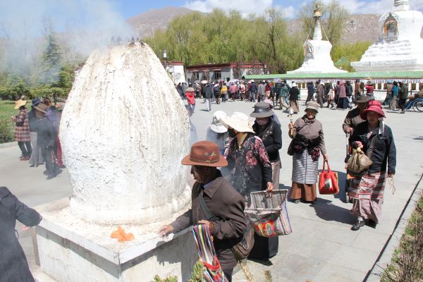 Mehrere Pilger sind in einem Kloster versammelt. Sie tragen Taschen bei sich.